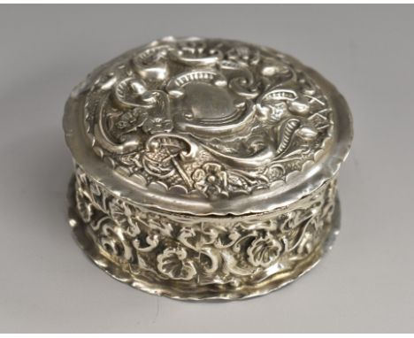 An Edwardian silver shaped circular dressing table trinket box, profusely chased with flowers, shells and scrolling foliage, 