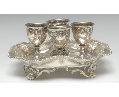 A Victorian silver shaped rectangular egg cruet, for four, the pedestal cups and wavy stand chased with strapwork, beaded bor