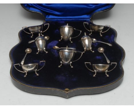 A George V eight piece silver cruet set, shaped rims, C-scroll and hoof feet, comprising four open salts, two pepper pots and