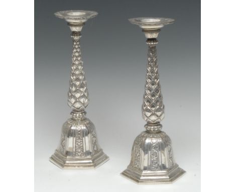 A pair of Indian silver candlesticks, broad circular sconces, lotus baluster pillars, domed hexagonal bases chased with folia