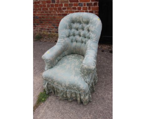 A button back armchair, upholstered in a light green brocade, on ebonised and castored supports 