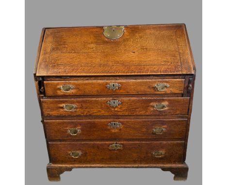 BUREAU - Georgian oak having a sloped front with large brass lock plate revealing a centre open drawer with three small drawe