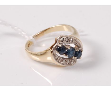 A sapphire and diamond ring, the three round sapphires, asymetrically set with three small round diamonds to either side, wit