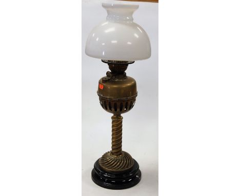 An early 20th century brass oil lamp having opalescent glass shade, brass reservoir, and swirled brass pedestal base