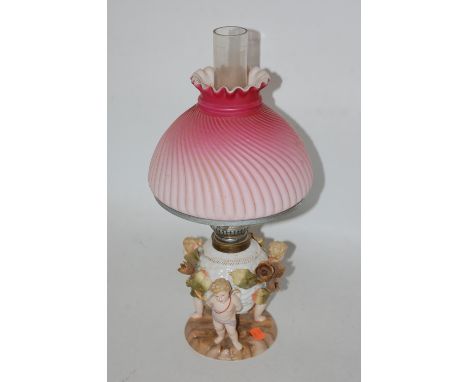 An early 20th century Meissen Dresden figural table lamp having a swirled pink tinted glass shade to an urn base supported by