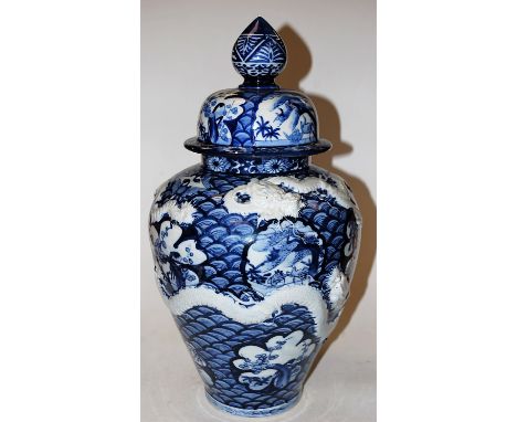 A large Chinese style stoneware blue and white vase and cover, of bluster form, relief decorated with dragons chasing a pearl