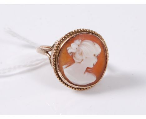 A cameo ring, the oval shell cameo collet set with rope twist border, plain band, indistinctly stamped '9ct', size Q, (3.8g)