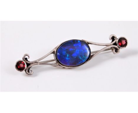 An opal doublet and garnet brooch, the oval opal doublet, approx. 16mm long, collet set to an open frame set with a round fac