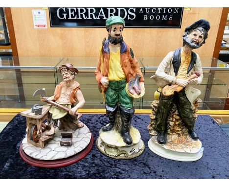 Three Capo di Monte Figures, comprising a man sharpening tools, a violin player and a fish seller, signed to base. Tallest 15