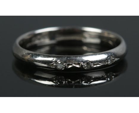 A mid twentieth century platinum ring, set with three diamonds to the band. Size L. Total weight: 3.1g.  