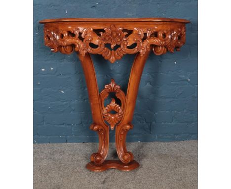A carved hardwood console table featuring floral scroll decoration. Approx. dimensions 84cm x 28cm x 89cm.  