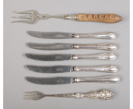 A collection of silver handled cutlery, together with a carved wooden handled bread fork. The majority of the silver handled 