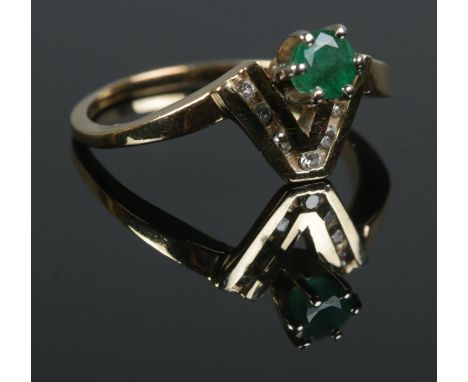 A modern emerald ring, set into a chevron of channel set small diamond. Tests to 14ct Gold. Size O. Total weight: 2.6g  