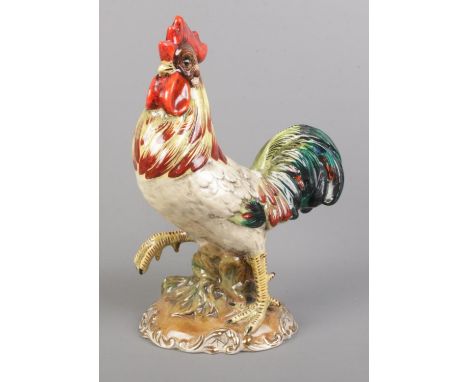 An Italian ceramic cockerel with gilt detailing to the base. 29cm high.  Paint peeling to some areas.