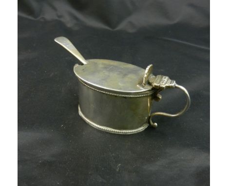 A late Victorian oval silver mustard pot and spoon, London 1893 and 1895 by Charles Boyton, with scroll handle and shell fini