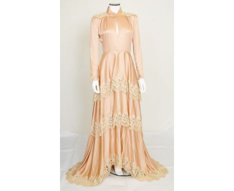 A vintage pale pink silk wedding dress with cream lace detailing to the shoulders and trim to the layered skirt, hidden 'peek