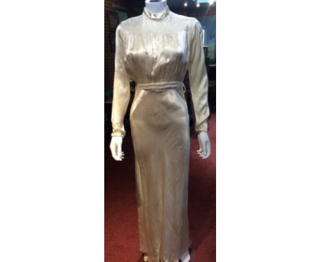 A 1930s cream satin wedding dress, embroidered and ruched bust with ruffle detail to neck, long sleeves, tie waist, train to 