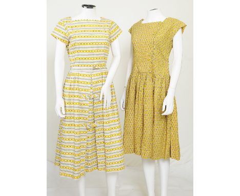 Two 1970s patterned yellow dresses by St Michael, one mustard yellow with a circular pink floral pattern, button fastening to