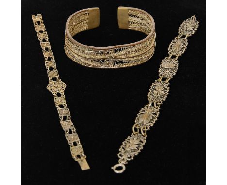 Two filigree patterned silver gilt metal bracelets and one bangle; one bracelet depicting bugs, leaves and a crest (3)