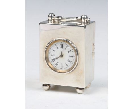 A LATE VICTORIAN RECTANGULAR SHAPED TIMEPIECE with bun feet and swing handle, French movement, white enamel dial and Roman nu