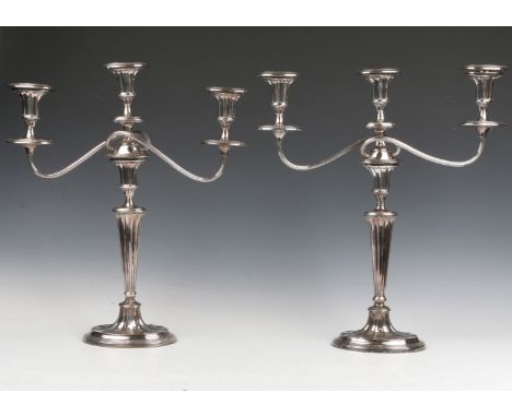 A PAIR OF SILVER PLATED TWO BRANCH THREE LIGHT CANDELABRA with tapering columns and scrolled arms, 45cm high