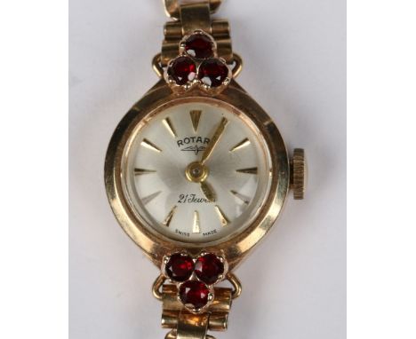 A LADY'S 9CT GOLD ROTARY WRIST WATCH with silvered dial and gilt batons, shoulders set with three garnets in each and with a 