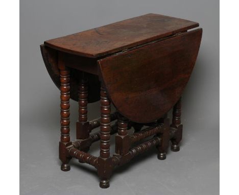 A SMALL OAK DROP LEAF TABLE, c.1700, the oval plank top and plain frieze raised on bobbin turned and block supports, similar 