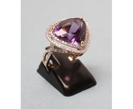 AN AMETHYST AND DIAMOND DRESS RING, the pear cut amethyst of approximate 6.85cts claw set to an open double border of numerou