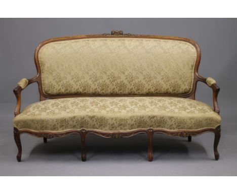 A VICTORIAN WALNUT AND PARCEL GILT SOFA in the Louis XV style, upholstered in gold floral silk brocade, the padded back with 