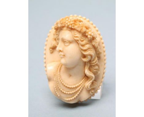 A LARGE VICTORIAN IVORY OVAL BROOCH/PENDANT, carved in high relief with the bust portrait of a young lady wearing a fruiting 