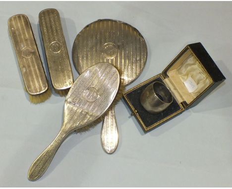 A silver-backed engine-turned hand mirror, two clothes brushes and a hairbrush marked 'Mary', London 1927/8, (a/f) and a case