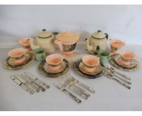 A cream and green enamel childs part tea set and a plastic part set.