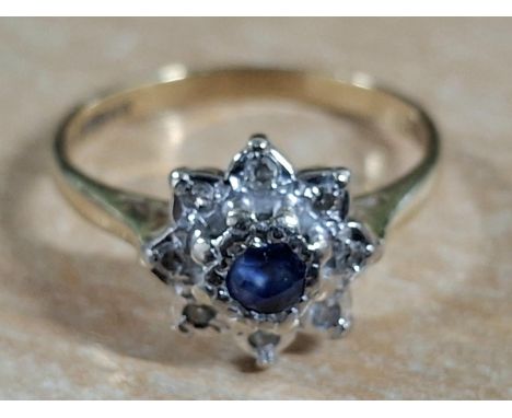 Hallmarked 18ct yellow gold flower ring with large, raised round cut Sapphire flanked by smaller, illusion set diamonds,3.5 g