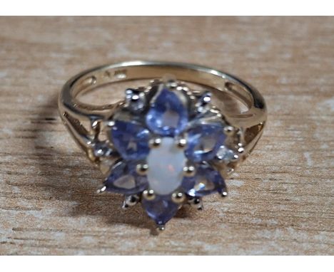 Flower ring with a central oval cut Opal surrounded by lilac coloured stones on a yellow gold coloured shank stamped 10K,2.5 