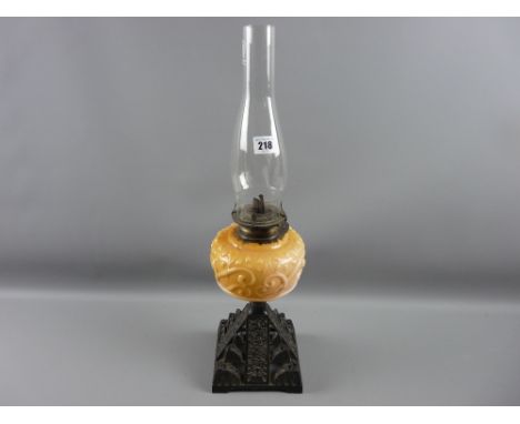 An iron based oil lamp with yellow tinted milk glass reservoir and chimney