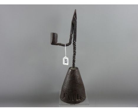 An 18th Century wrought iron rush nip light on a conical stained oak holder having simple punched decoration around the base 