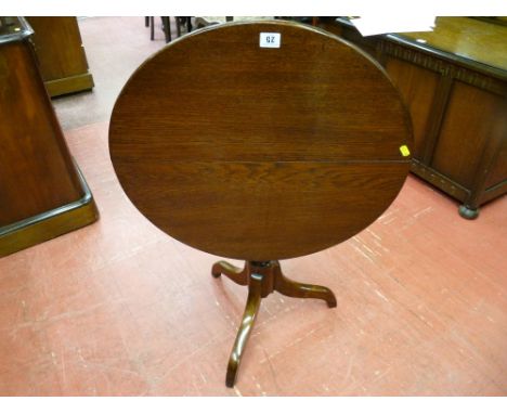 An antique oak tilt top table on turned column tripod base (legs reduced), 60 cms diam top