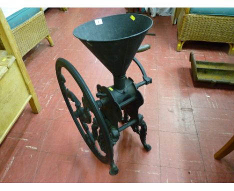 An antique cast iron floor standing grocer's coffee grinder with wooden winding handle, 78 cms high, 53 cms wide