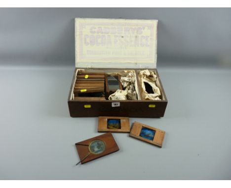 A quantity of mahogany framed hand painted Magic Lantern slides, some with changing views in a vintage Cadbury's Cocoa lidded