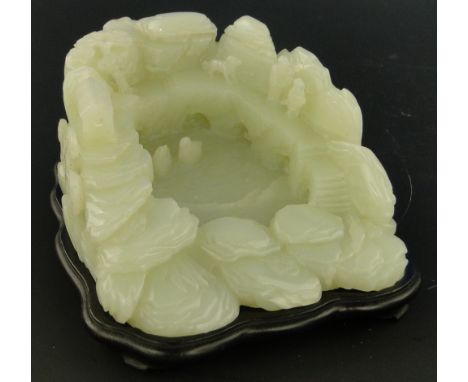 A Chinese carved white jade brush washer
modelled as a pool with ducks and water-lillies, and figures around the edge, length