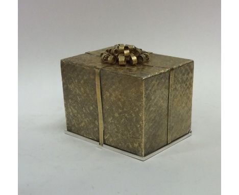 STUART DEVLIN: A novelty silver and silver gilt box in the form of a gift with hinged top revealing swans and cygnets on blue