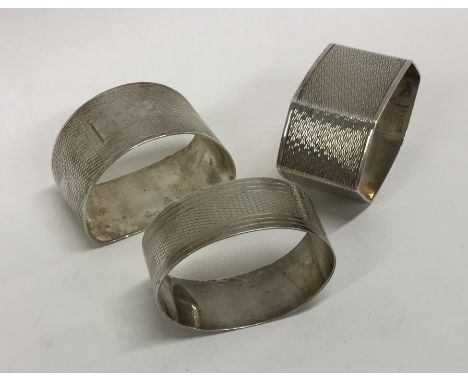 Three silver engine turned napkin rings. Approx. 63 grams. Est. £20 - £30.