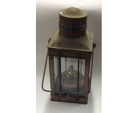 A copper mounted oil lamp of rectangular form with swing handle. Est. £30 - £50.