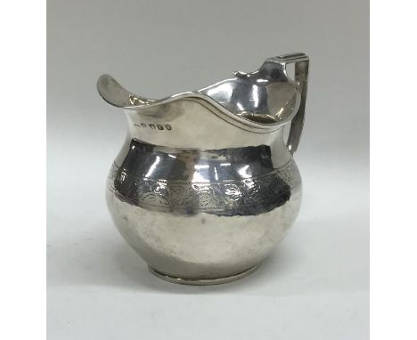 A Georgian silver squat cream jug with floral decoration. London. By SH. Approx. 107 grams. Est. £65 - £75.