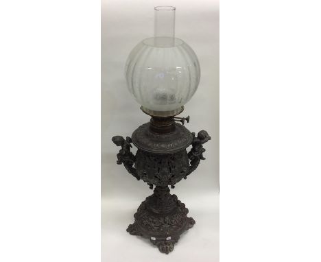 A massive cast oil lamp mounted with cherubs. Est. £30 - £50.