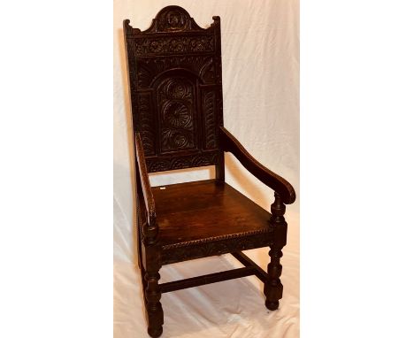 A 17th Century revival oak wainscot chair, serpentine rail, heavily carved in a Jacobean manner, scrolling arm rest, two plan