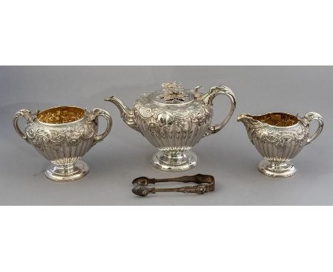 An early Victorian silver three piece tea set, fluted circular shapes with scroll work and a floral finial to the teapot, pre