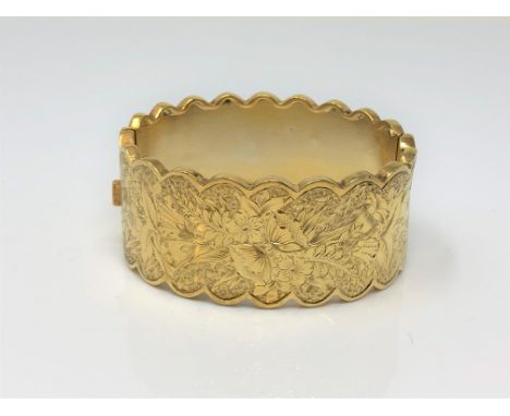 An ornate late Victorian gold plated hinged bangle with engraved decoration CONDITION REPORT: Two shallow dents near the hing
