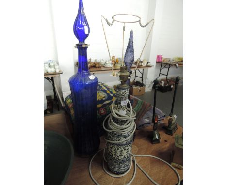 Two tall blue glass bottles with stoppers and a table lamp