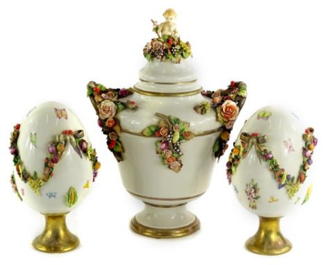 A Capodimonte porcelain garniture, the central two handled urn embellished with fruit, flowers and with a putti knop to the r